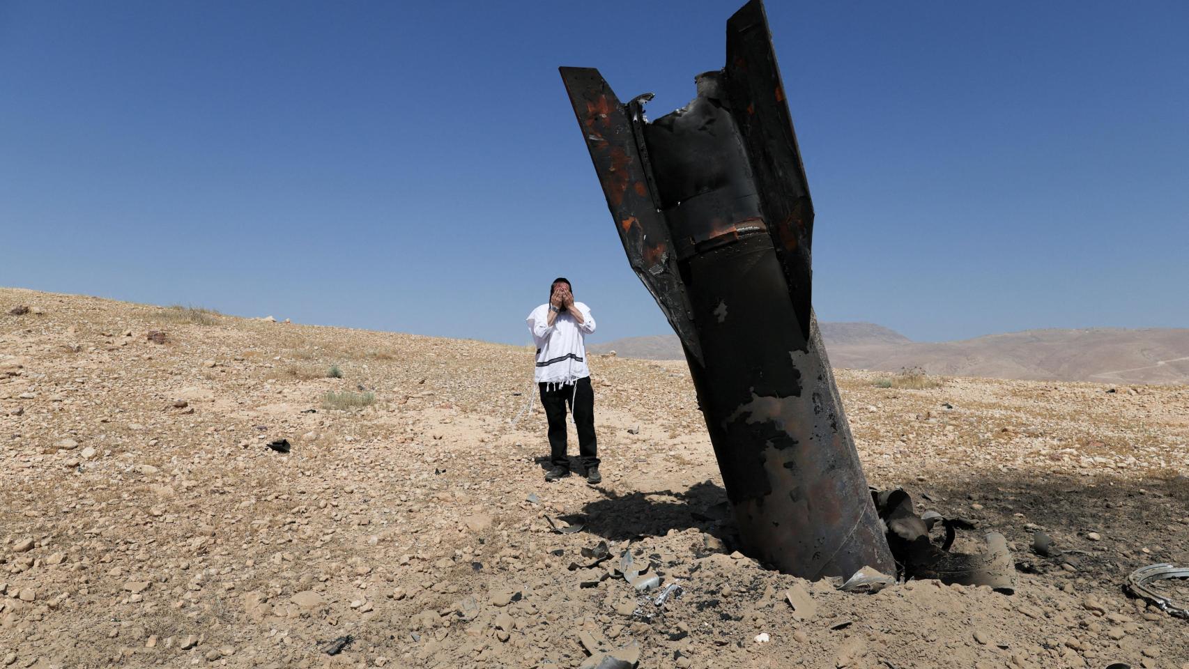 Personal de seguridad y rescate israelí trabaja junto a un fragmento de un proyectil tras un ataque con misiles lanzado desde Irán a Israel.