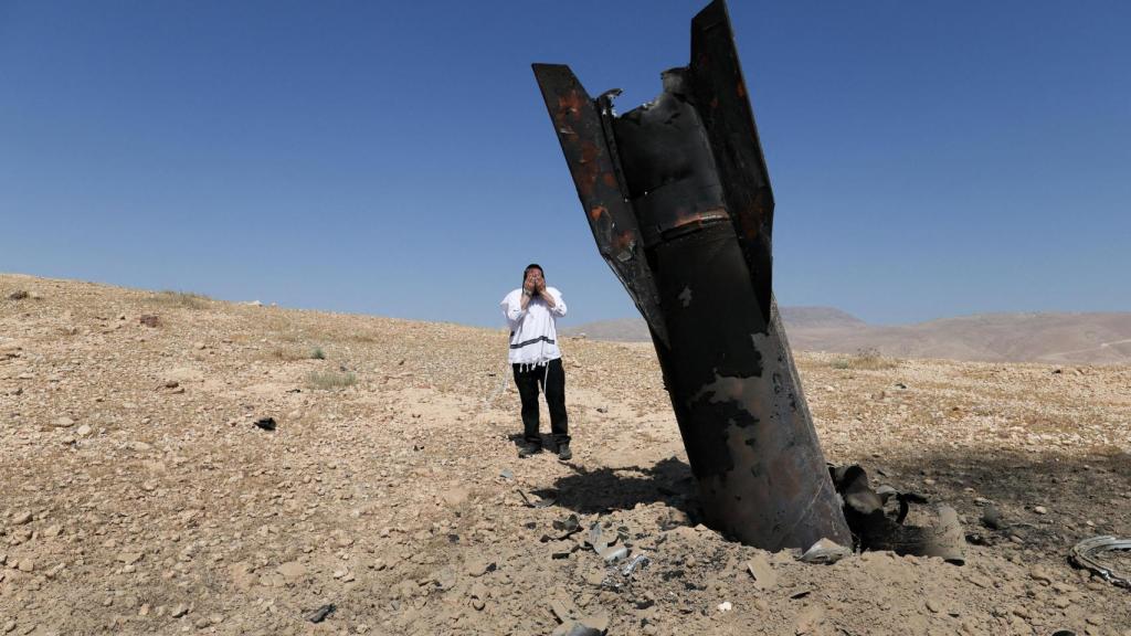Personal de seguridad y rescate israelí trabaja junto a un fragmento de un proyectil tras un ataque con misiles lanzado desde Irán a Israel.