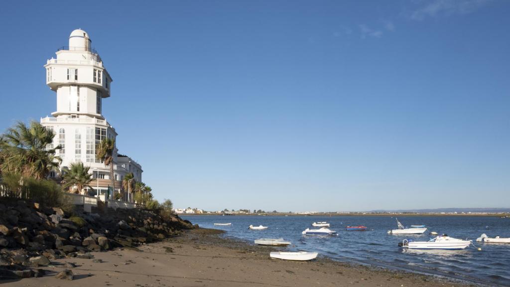 Faro de Isla Cristina y pequeños barcos pesqueros junto a la arena.