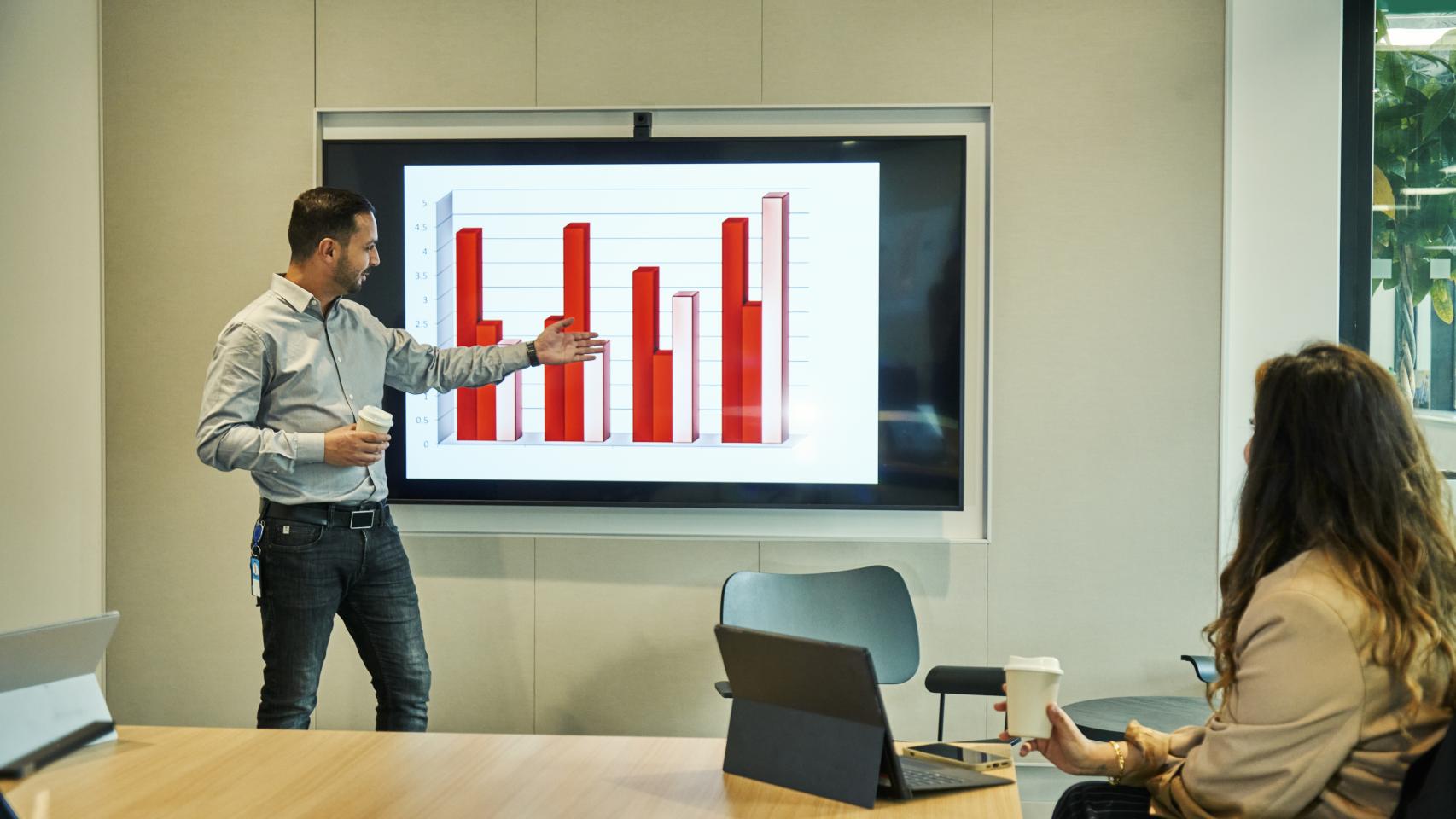 Un hombre explicando algunos gráficos en una pantalla.