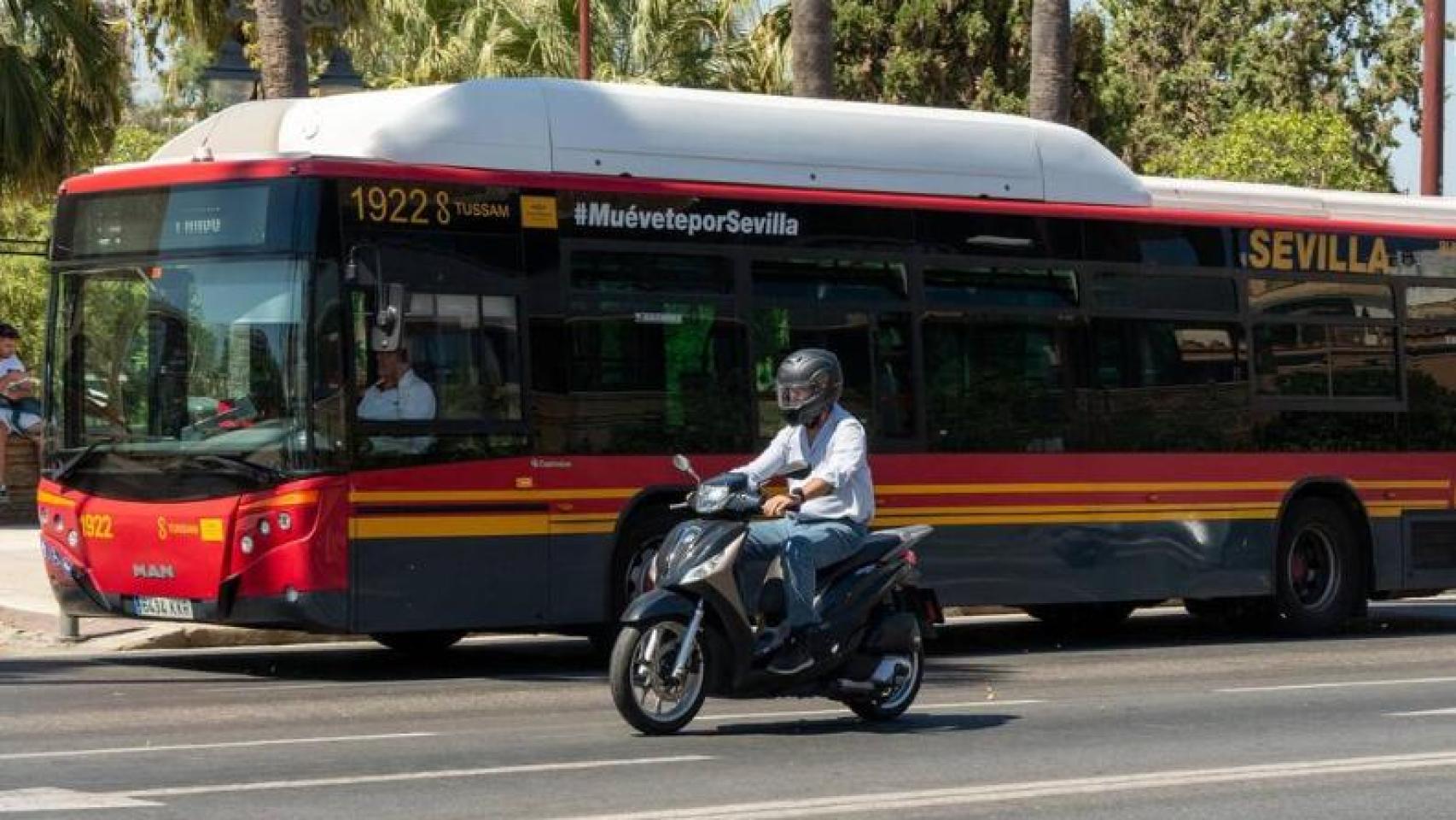 Una motocicleta circula junto a un autobús de Tussam en el Paseo de Colón.-EP