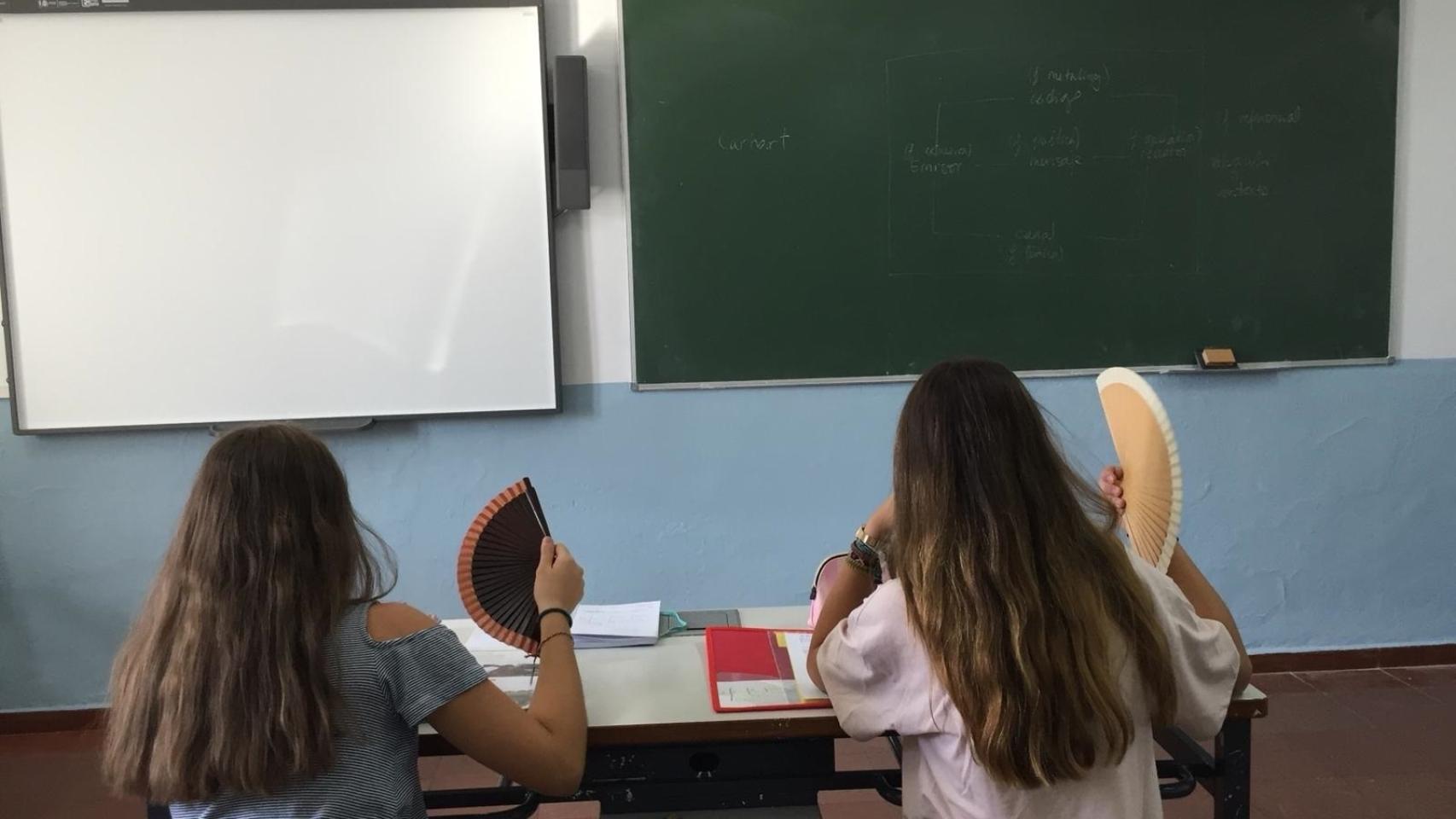 Foto de archivo de escolares con abanico en el aula.