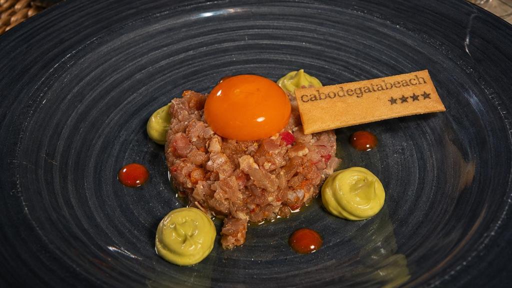 Tartar de atún macerado con soja, naranja y yema de huevo curada, acompañado de tostas de brioche.