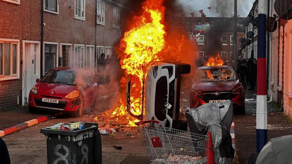 Coches ardiendo en la calle Lendrick de Belfast, tras los disturbios por el apuñalamiento de un hombre a manos de un refugiado de origen sirio.