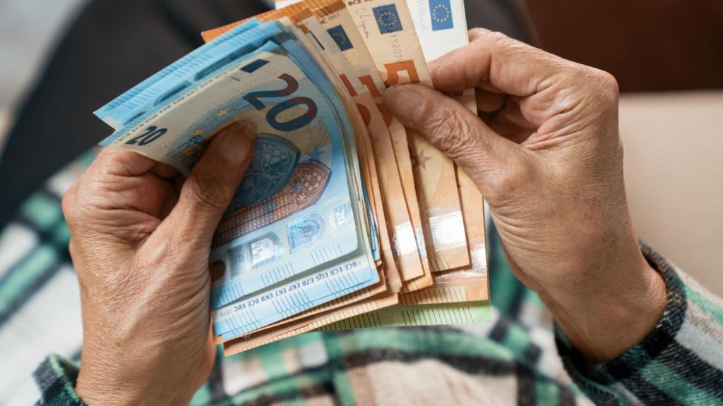 Mujer mayor sosteniendo varios billetes de euro.