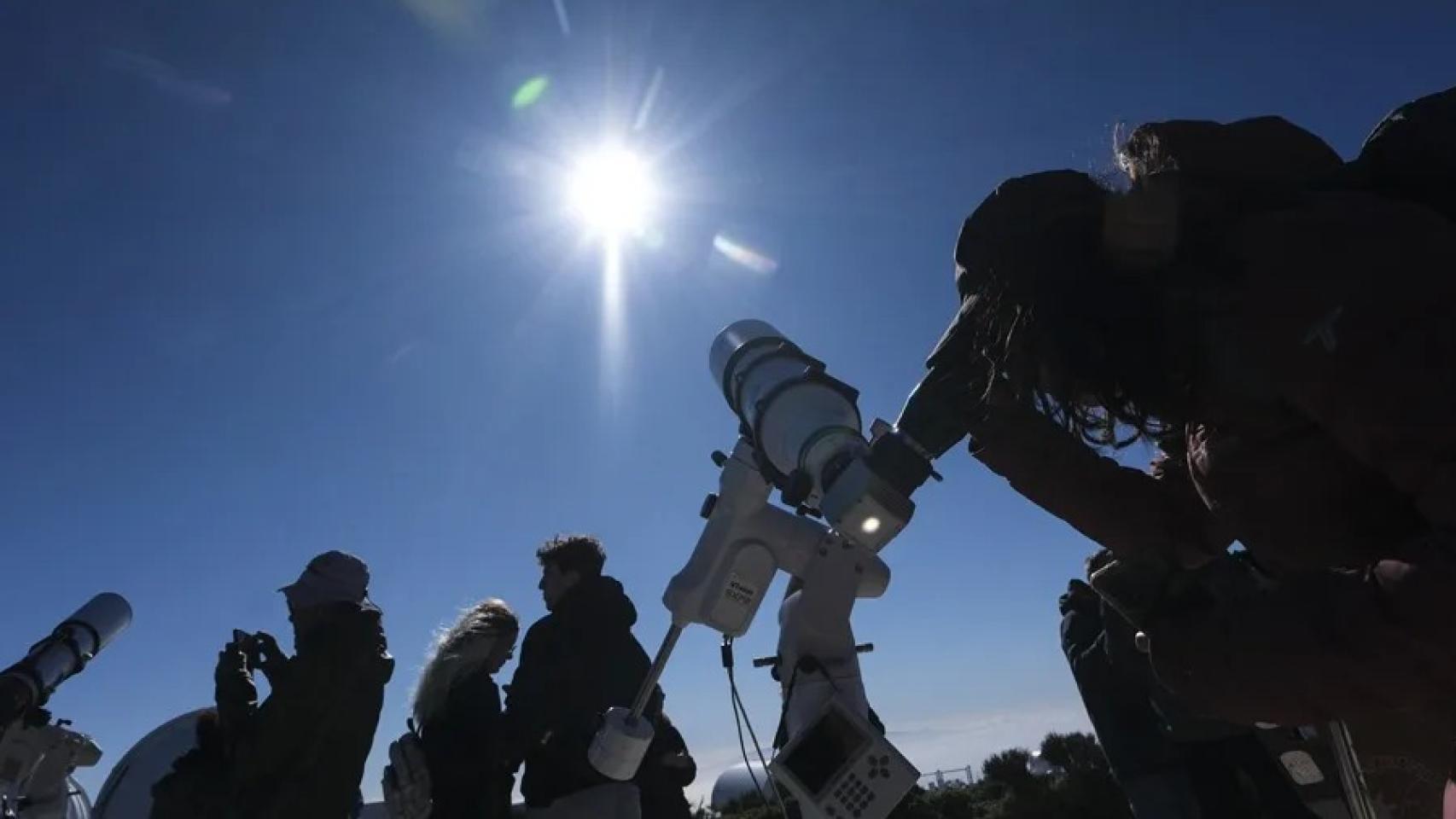 Un grupo de personas observa un eclipse solar en la montaña. 