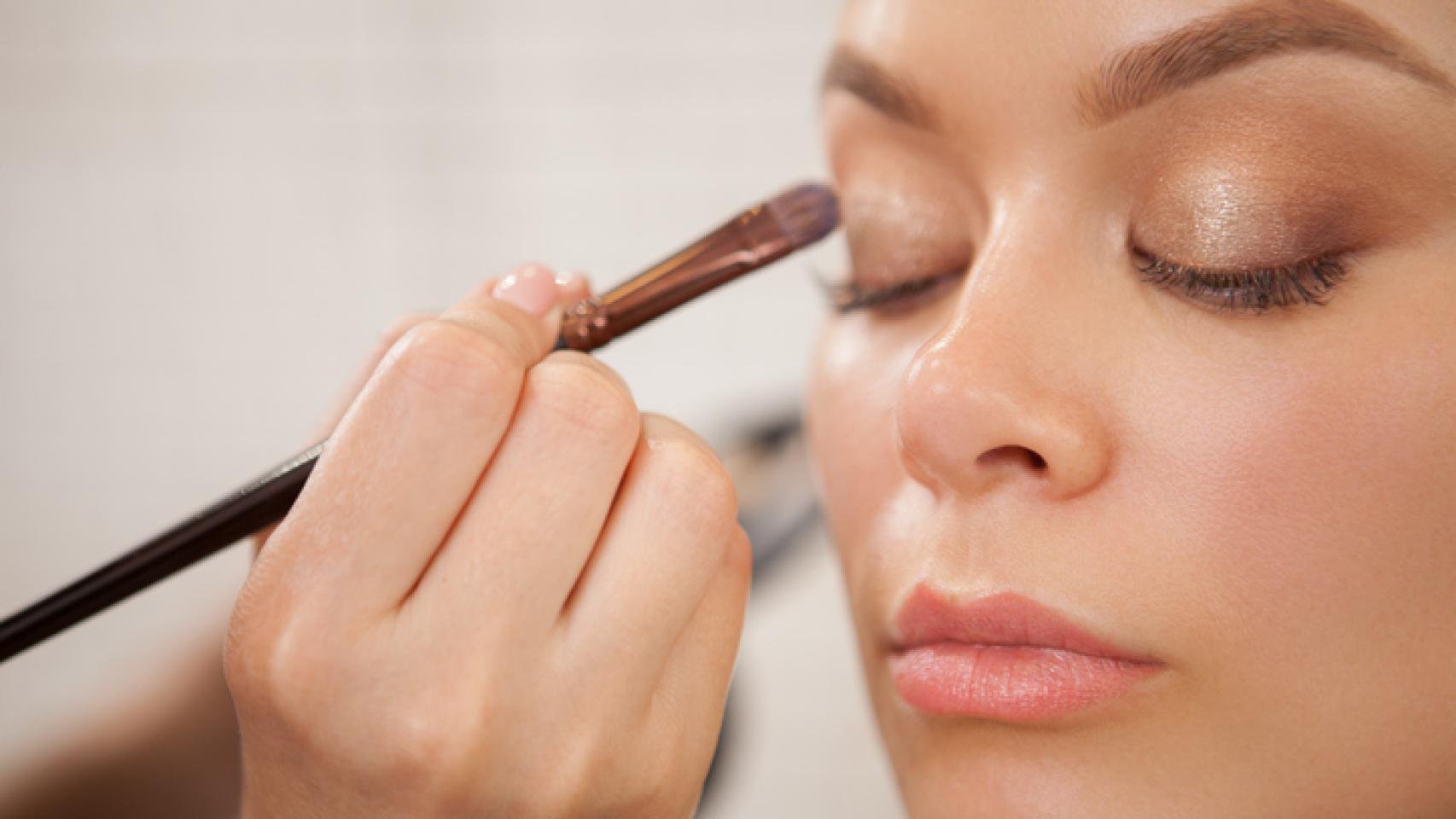 Maquilladora aplicando sombra de ojos en el párpado. 