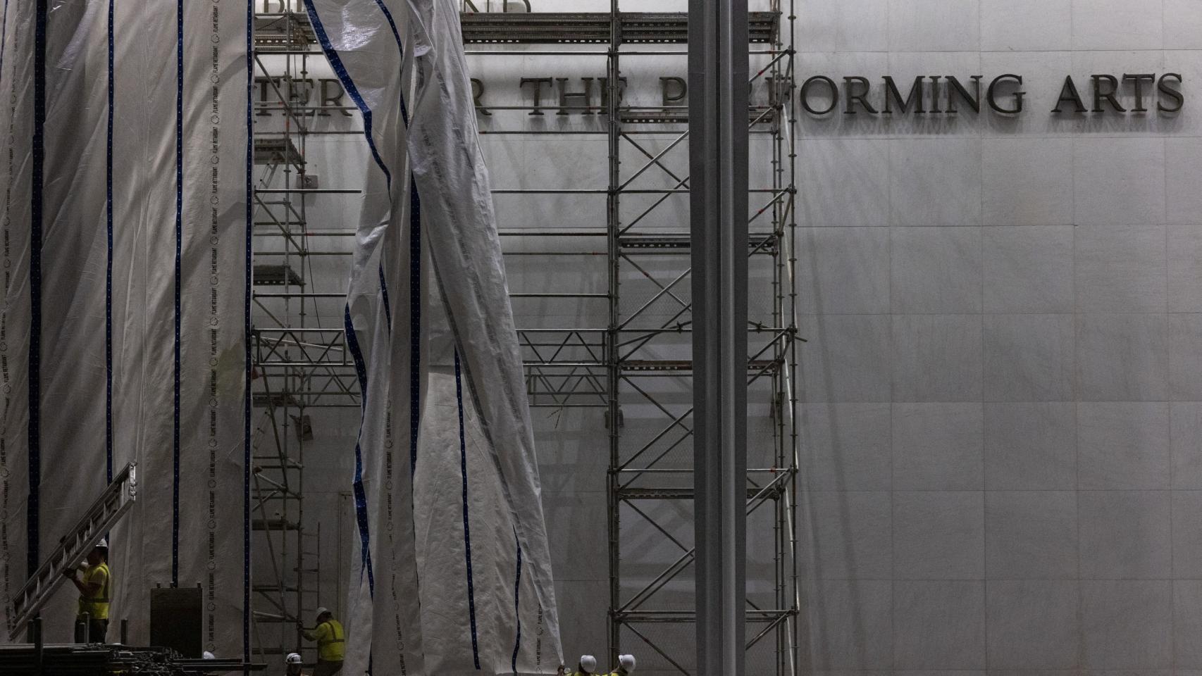 Trabajadores levantan una lona para preparar la retirada de las letras de la fachada del Centro Conmemorativo John F. Kennedy para las Artes Escénicas, tras la orden de un juez federal de eliminar el nombre del presidente estadounidense Donald Trump de la institución, en Washington. 