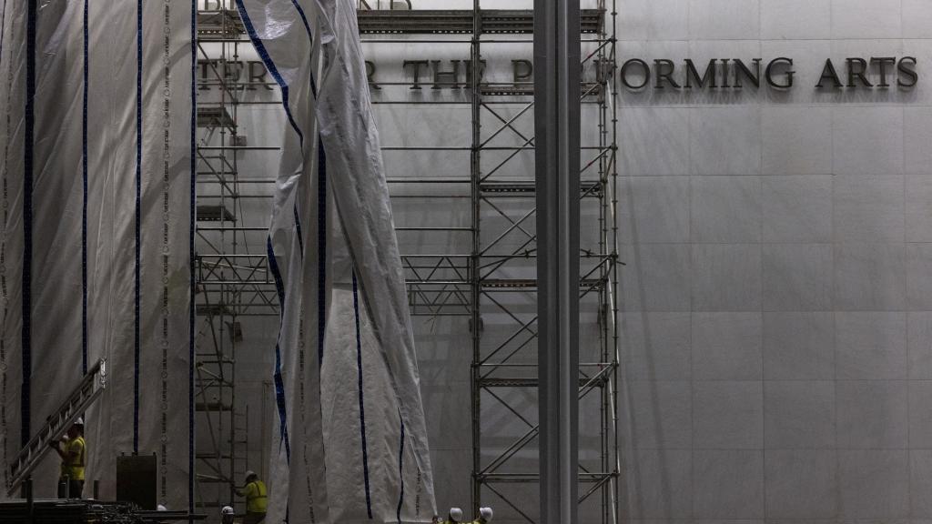 Trabajadores levantan una lona para preparar la retirada de las letras de la fachada del Centro Conmemorativo John F. Kennedy para las Artes Escénicas, tras la orden de un juez federal de eliminar el nombre del presidente estadounidense Donald Trump de la institución, en Washington. 