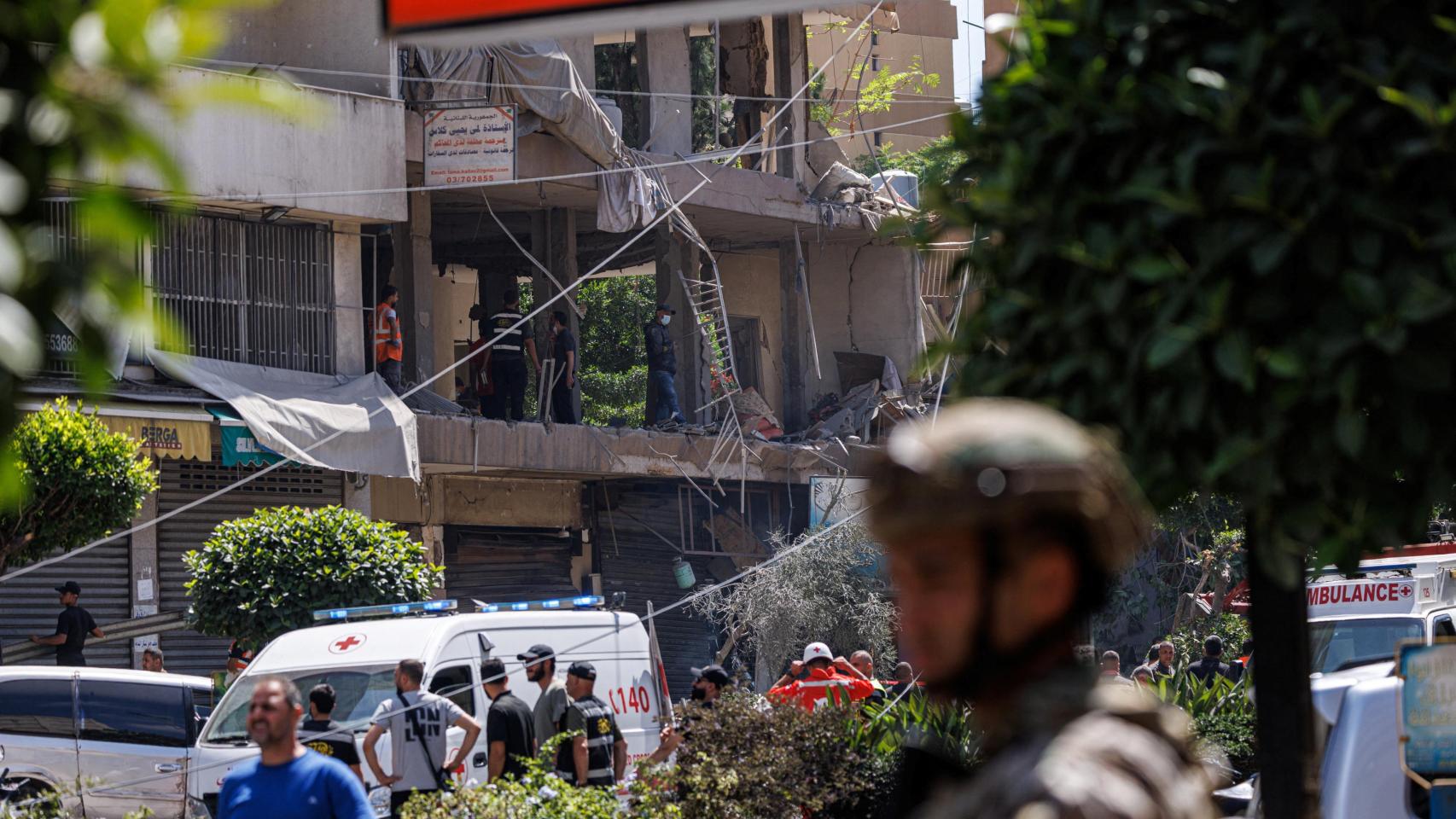 Un oficial del ejército libanés permanece de pie mientras agentes de policía y personal de emergencia trabajan en el lugar de un ataque israelí en los suburbios del sur de Beirut. 