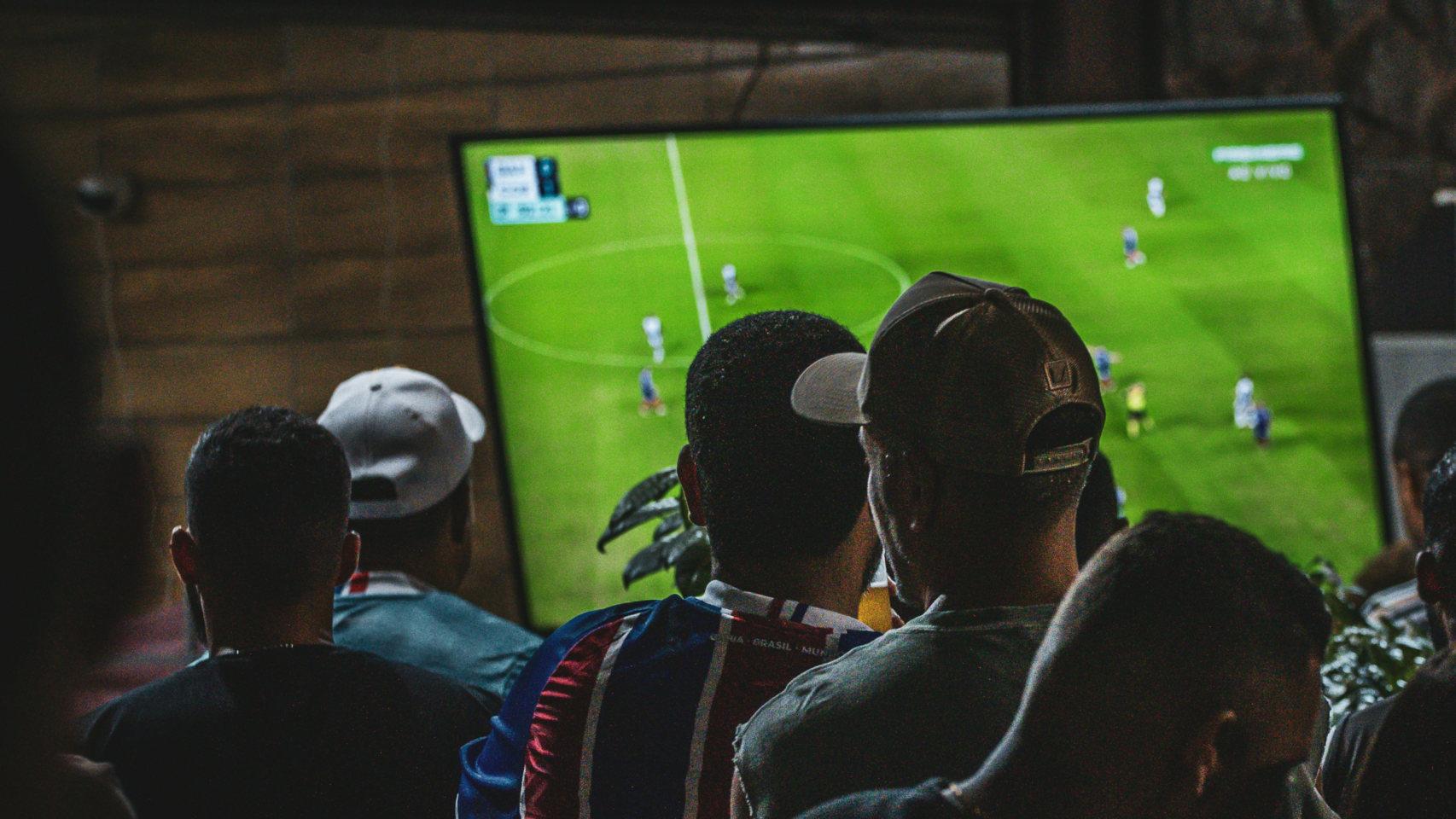 Un grupo de aficionados ve un partido de fútbol en un televisor