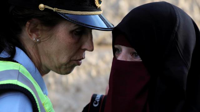 Una agente de seguridad junto a una mujer con niqab.