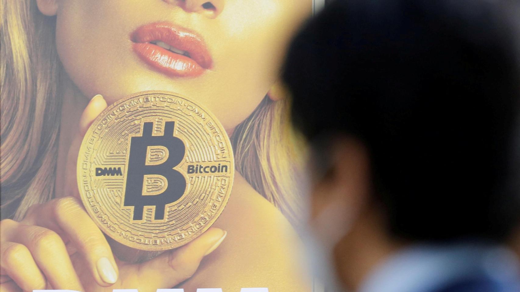 Un hombre se encuentra cerca de un anuncio de una plataforma de intercambio de criptomonedas en Tokio.