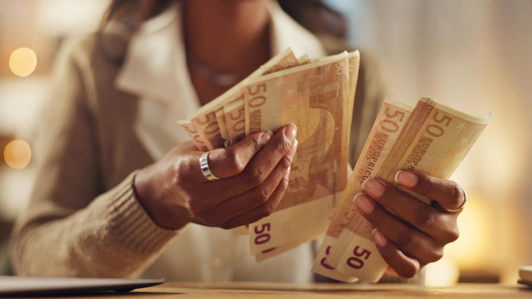 Una mujer contando dinero en efectivo.
