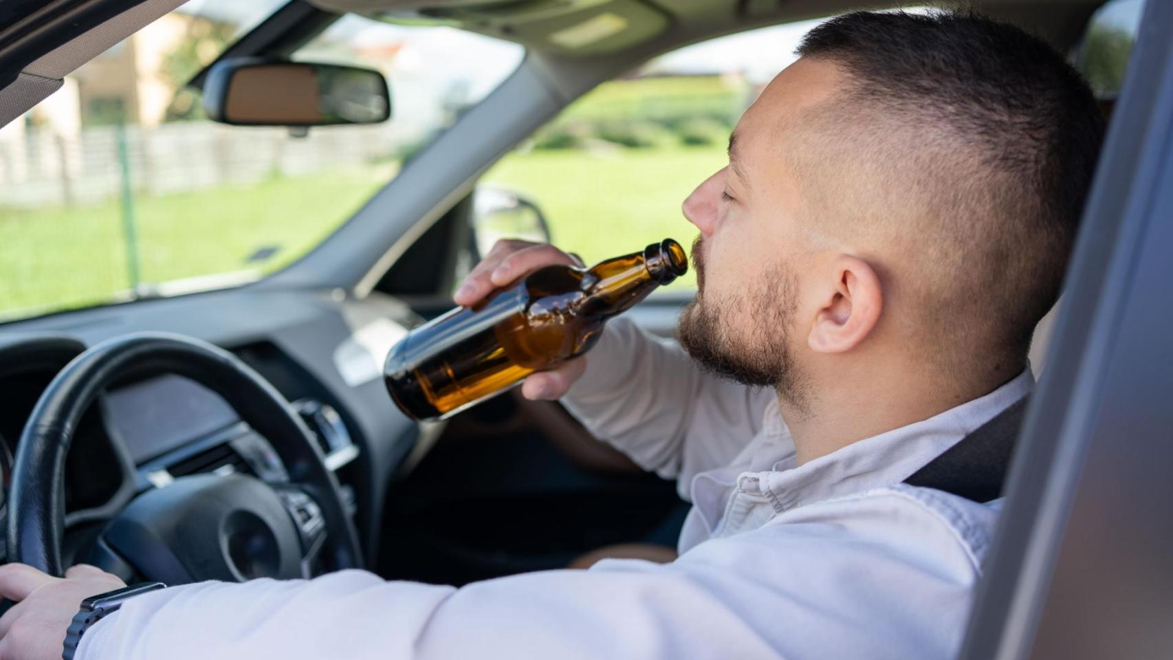 Un hombre bebe alcohol mientras conduce