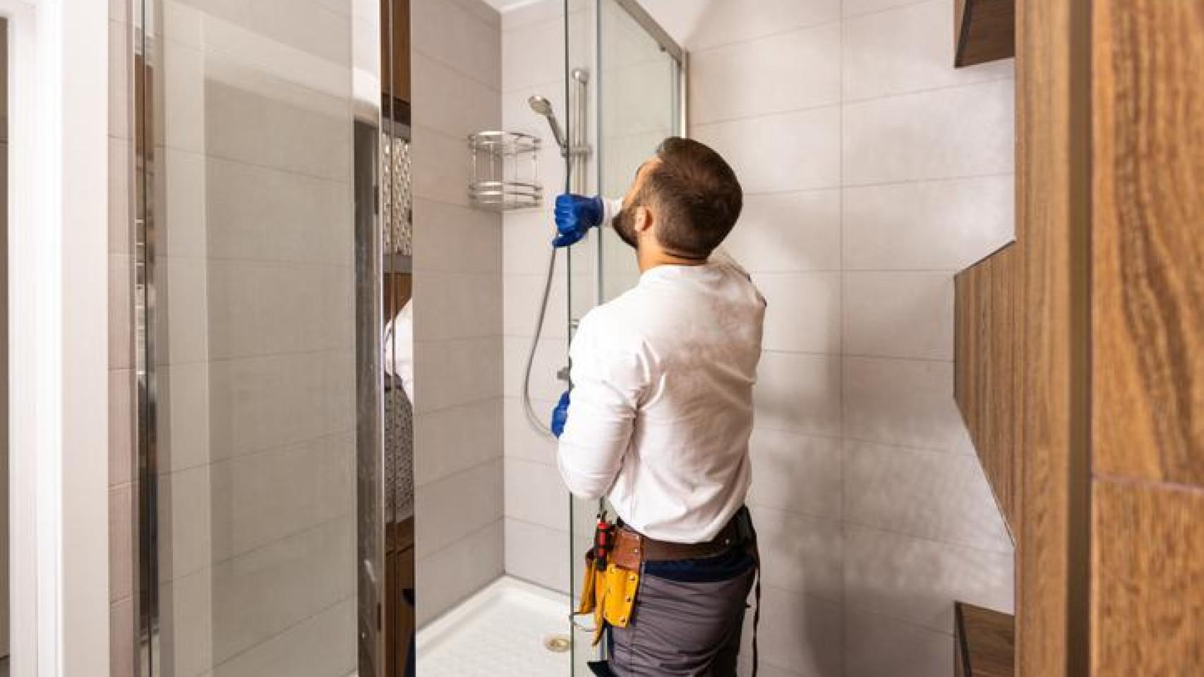 Un fontanero cambiando una bañera por una ducha.