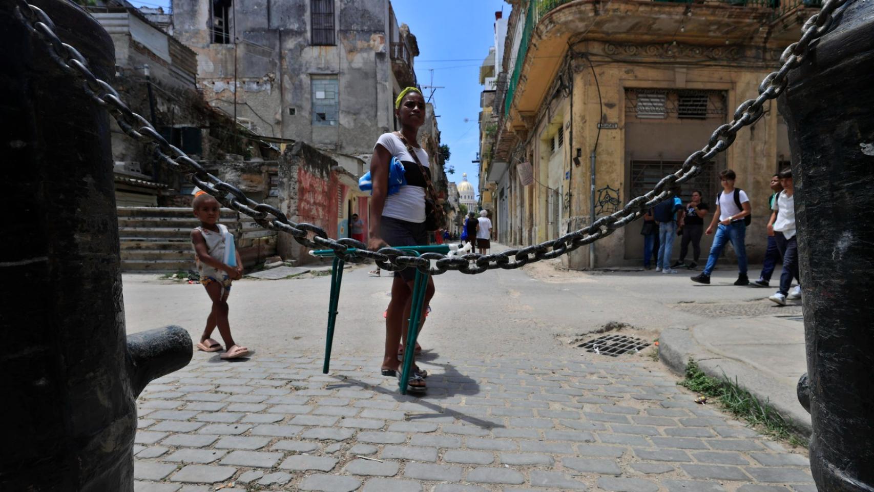 Una mujer en plena calle en Cuba detrás de una cadena.