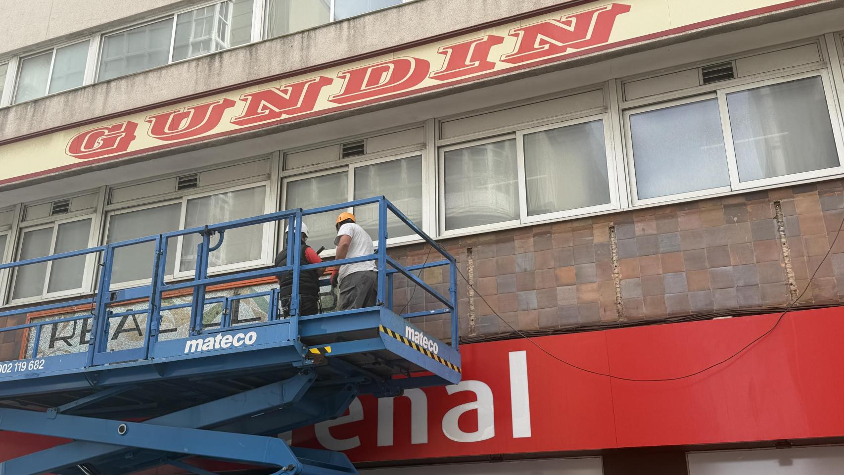 Operarios trabajando en la retirada del cartel exterior.