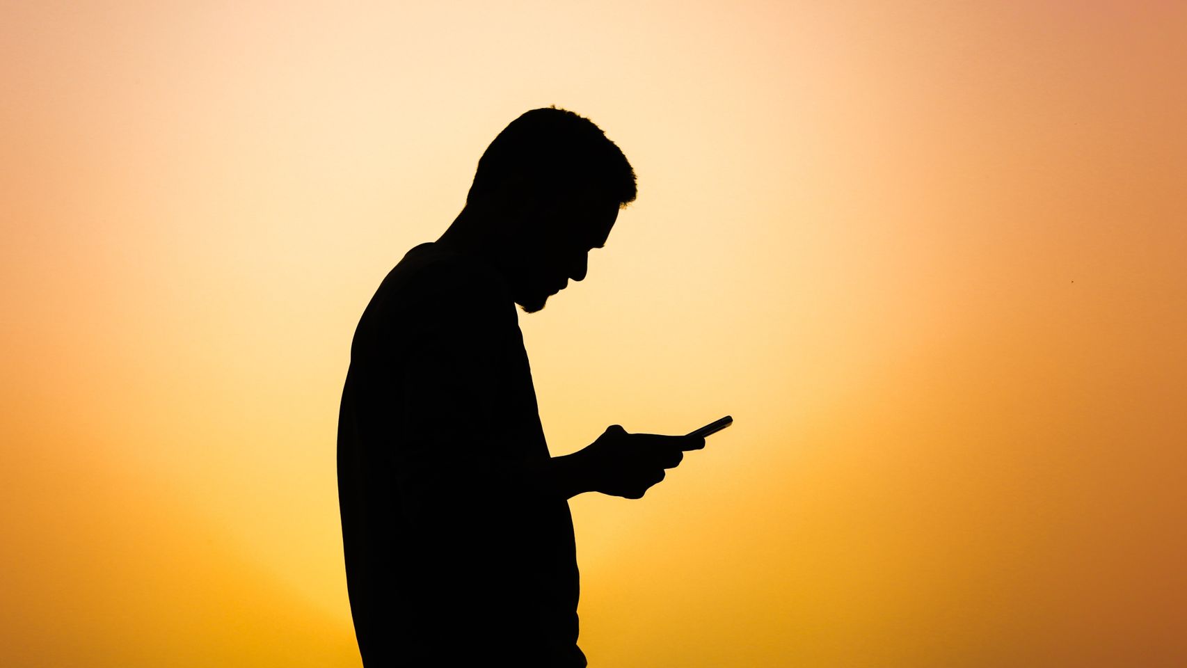 Silueta de un hombre utilizando su teléfono móvil.