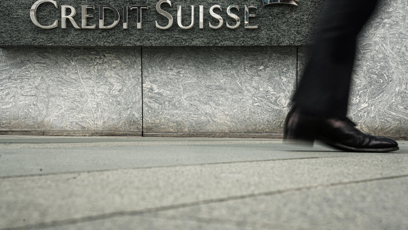 Una persona camina delante de la sede de Credit Suisse en Hong Kong.