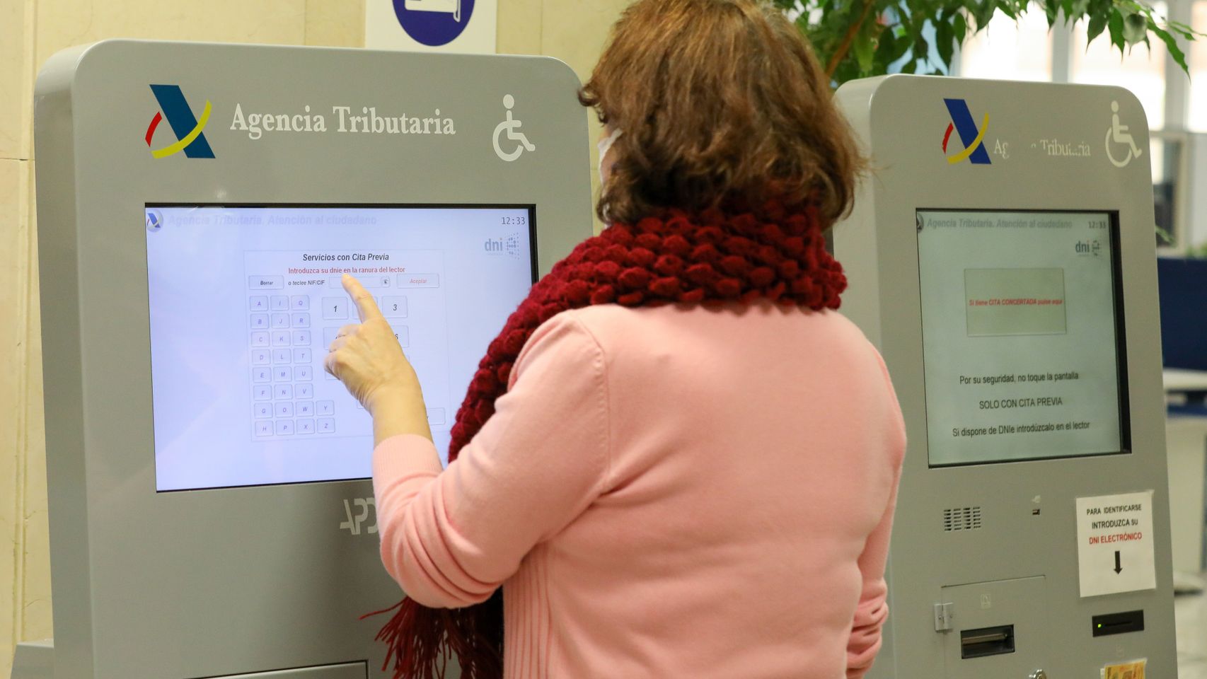 Una jubilada pide turno en una oficina de la Agencia Tributaria.
