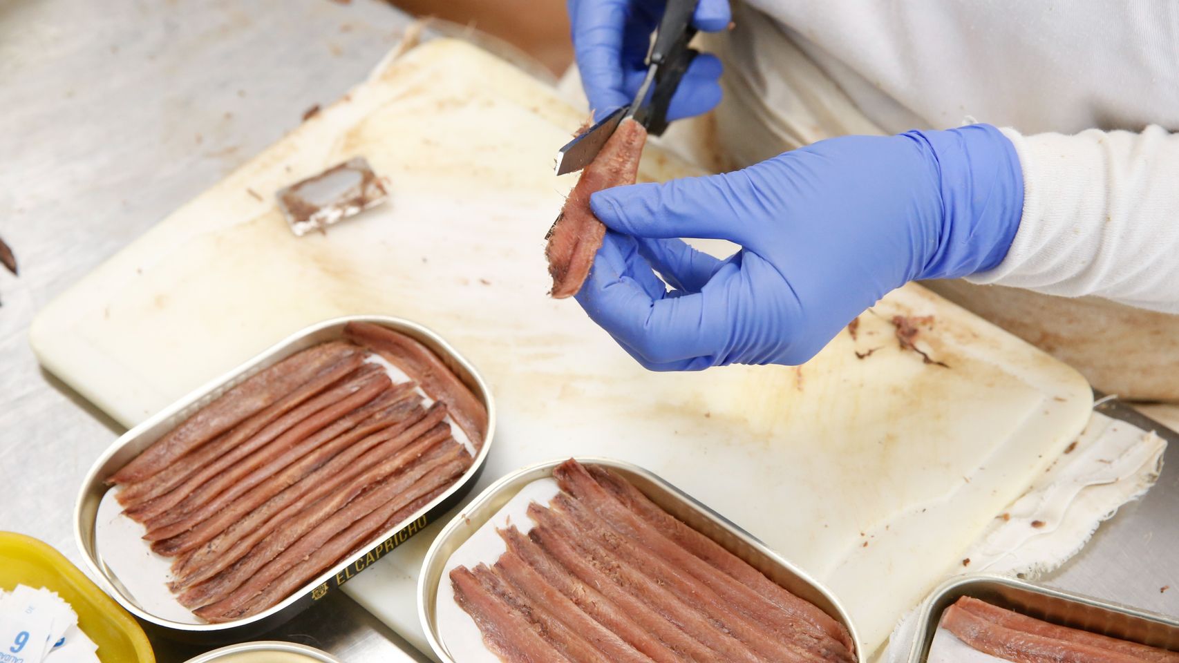 Una trabajadora prepara una lata de anchoas.