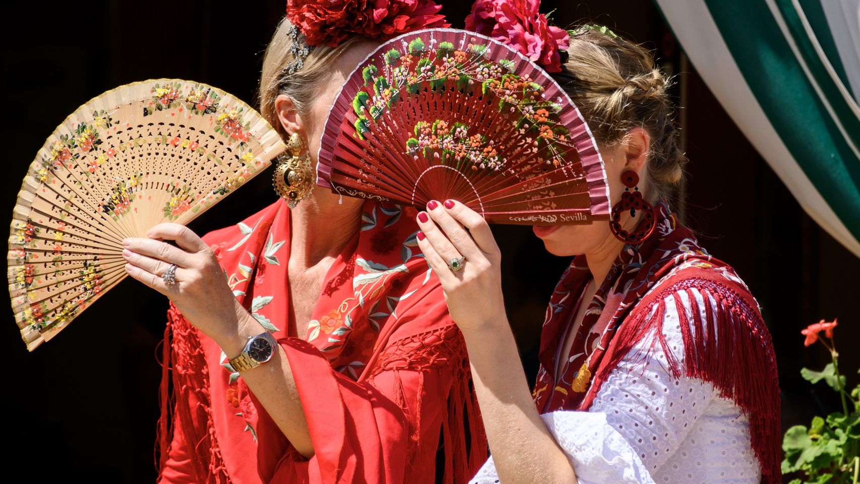 Dos mujeres vestidas de flamenca se protegen del sol en la Feria.