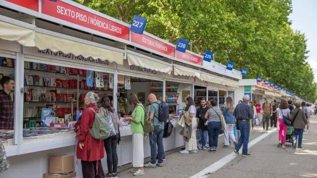 Algunas personas pasean y compran libros en la Feria del Libro de Madrid.