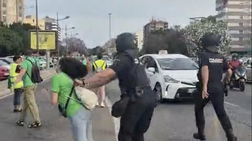 El policía empujó a la manifestante y la tiró al suelo. EE