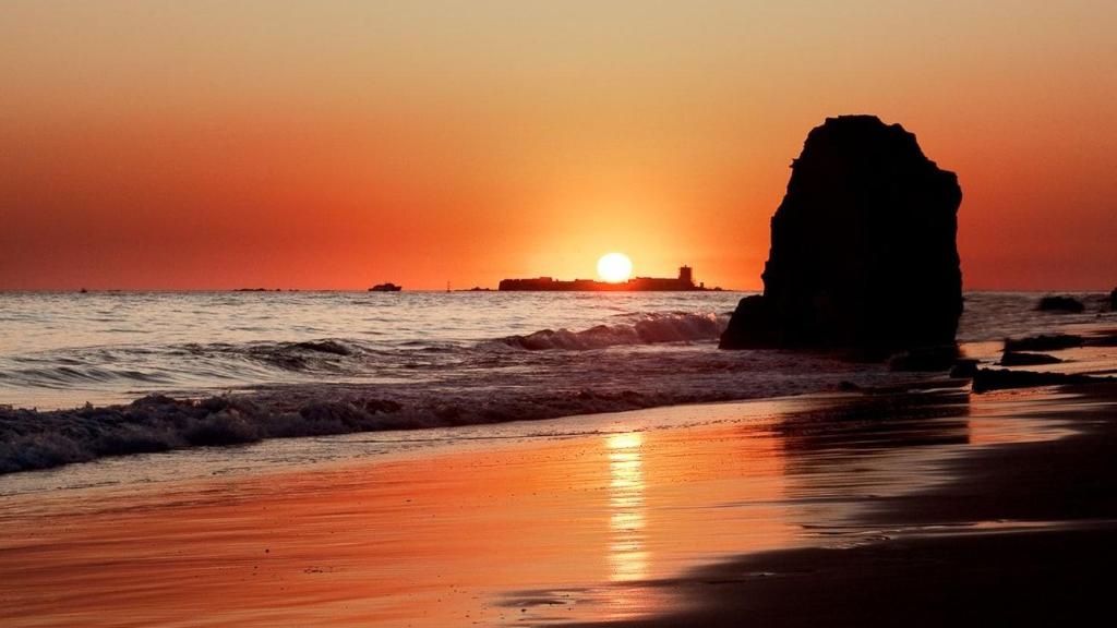 La silueta del castillo de Sancti Petri en la playa de La Barrosa al atardecer.