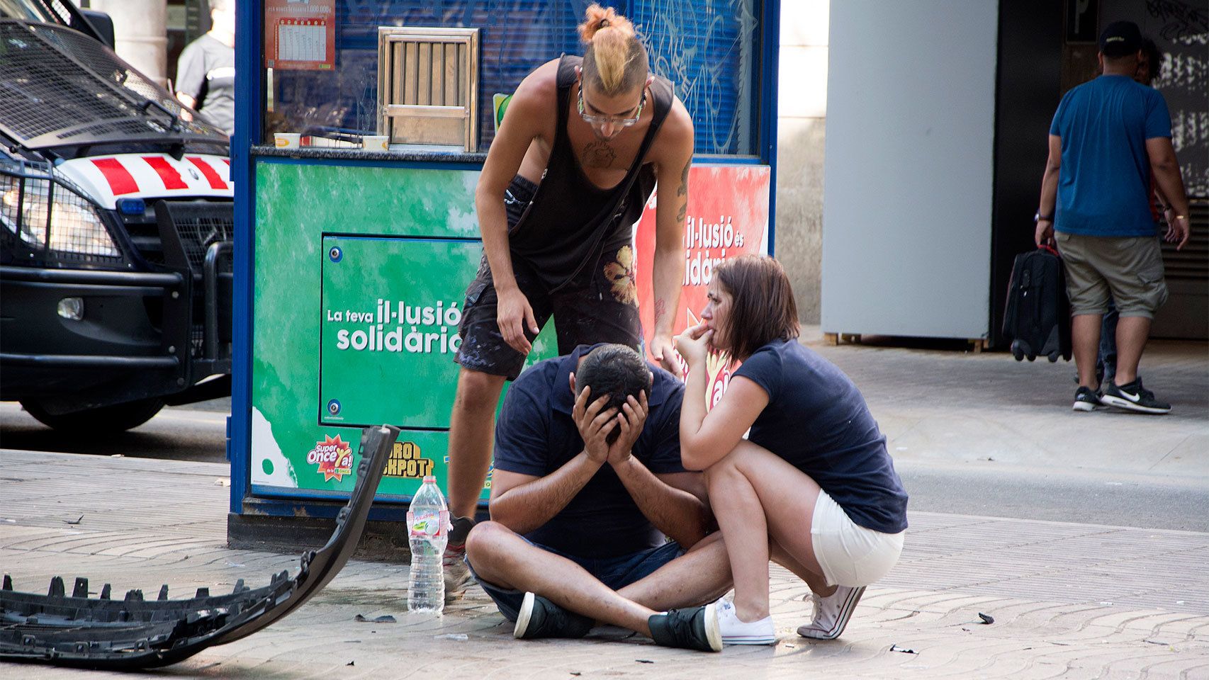 Varios jóvenes permanecen junto a los restos de un vehículo en el lugar del atentado.