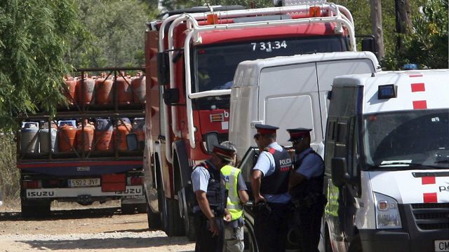 Mossos y bomberos frente al camión con las bombonas de butano.
