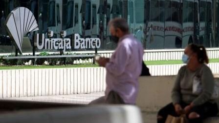 Dos personas frente a la sede de Unicaja en Málaga.