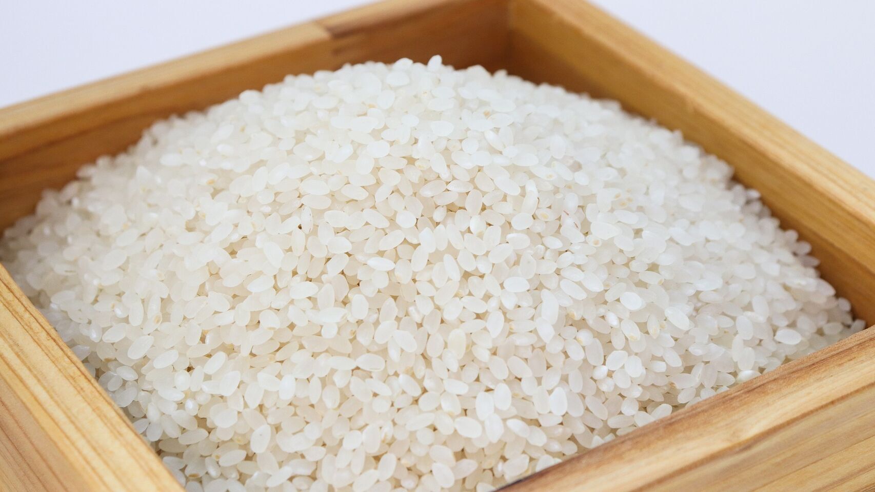 Una caja de madera con arroz crudo.