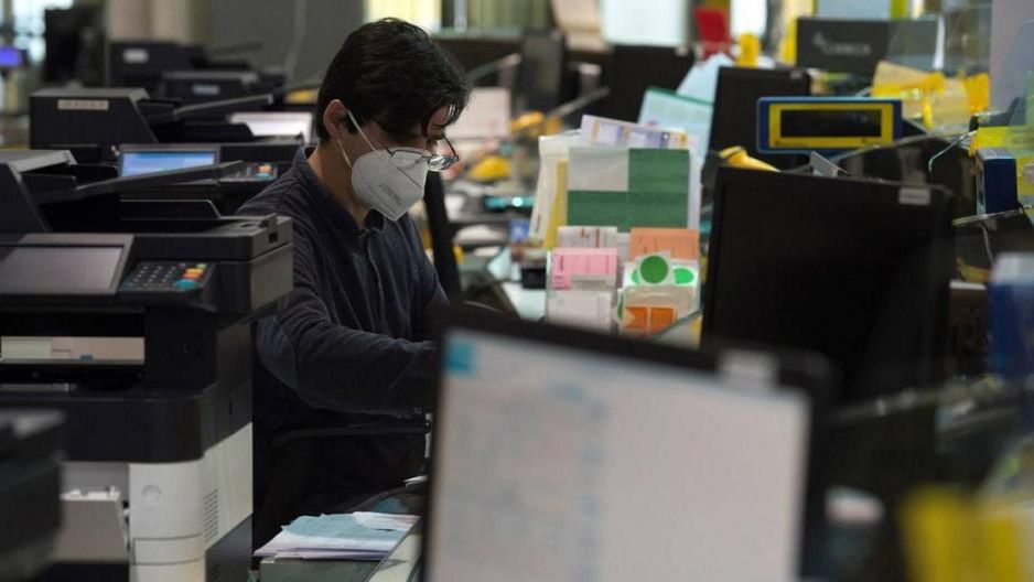 Un trabajador llevando mascarilla en una oficina.