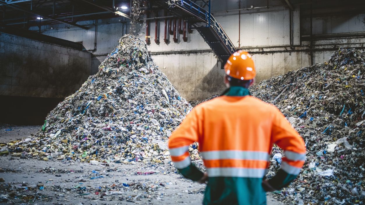 Un trabajador de una planta de reciclaje observando el proceso de gestión de residuos.